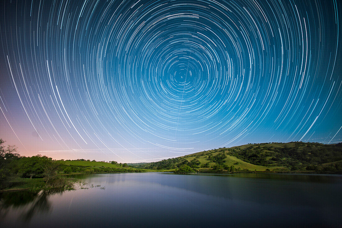 Beautiful scenery with star trails above lake at dusk, San Jose, California, USA