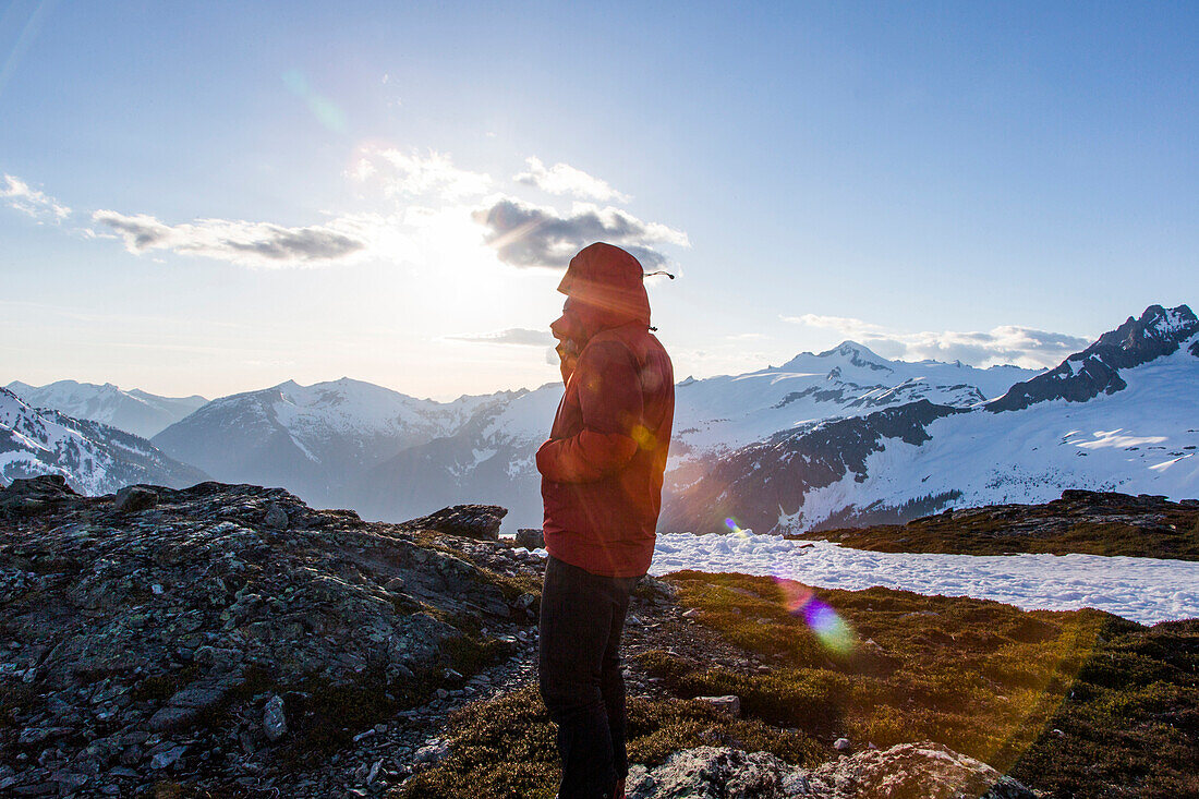 Seitenansichtphotographie des Mannes in der Winterjacke, die in den schneebedeckten Bergen an Sahale-Arm von Sahale-Spitze, Nordkaskaden-Nationalpark, Washington State, USA steht.