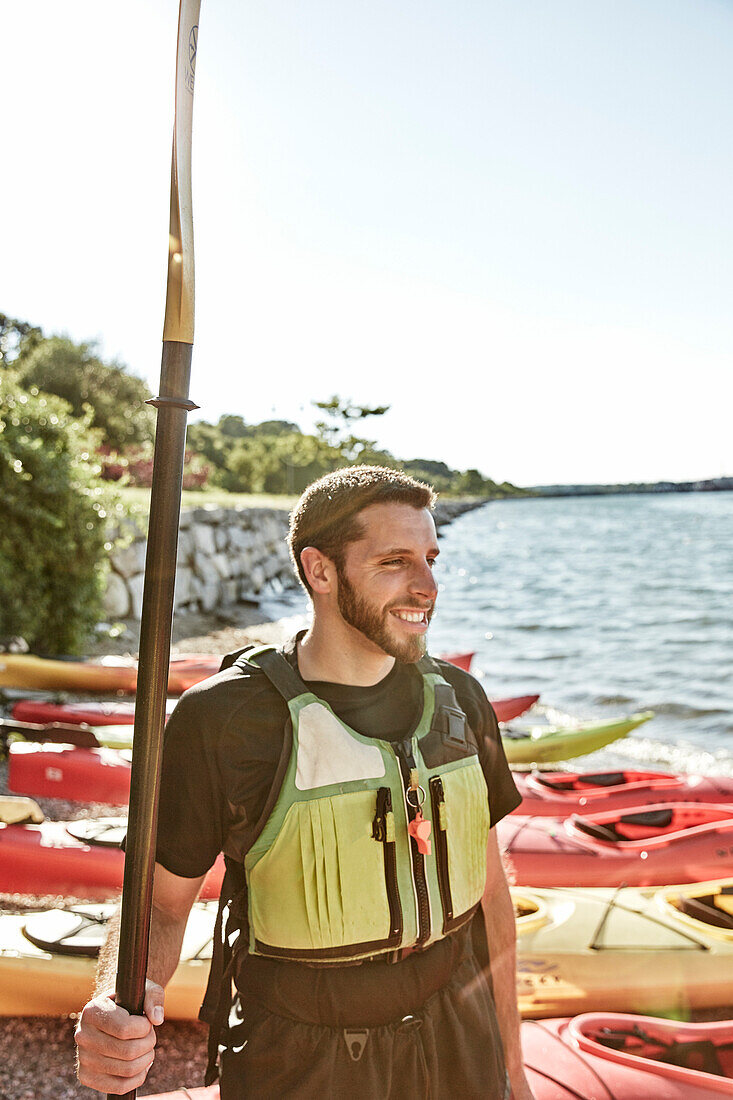 Photograph of smiling young man with sea kayak paddle, Portland, Maine, USA