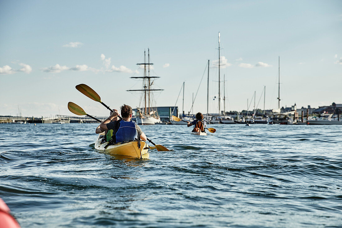 Hintere Ansicht von zwei Männern, die im Tandemseekajak, Casco Bay, Portland, Maine, USA schaufeln.