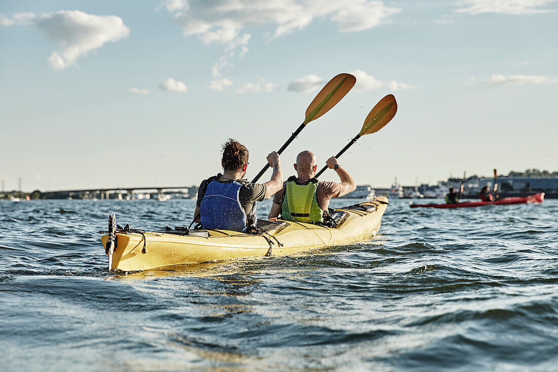 Photograph of two men paddling in tandem sea kayak, Portland, Maine, USA