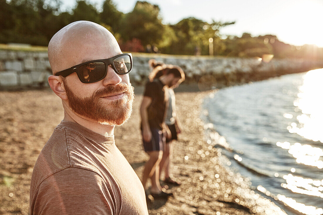 Photograph with selfie of young man in sunglasses with beard and mustache on beach, Casco Bay, Portland, Maine, USA