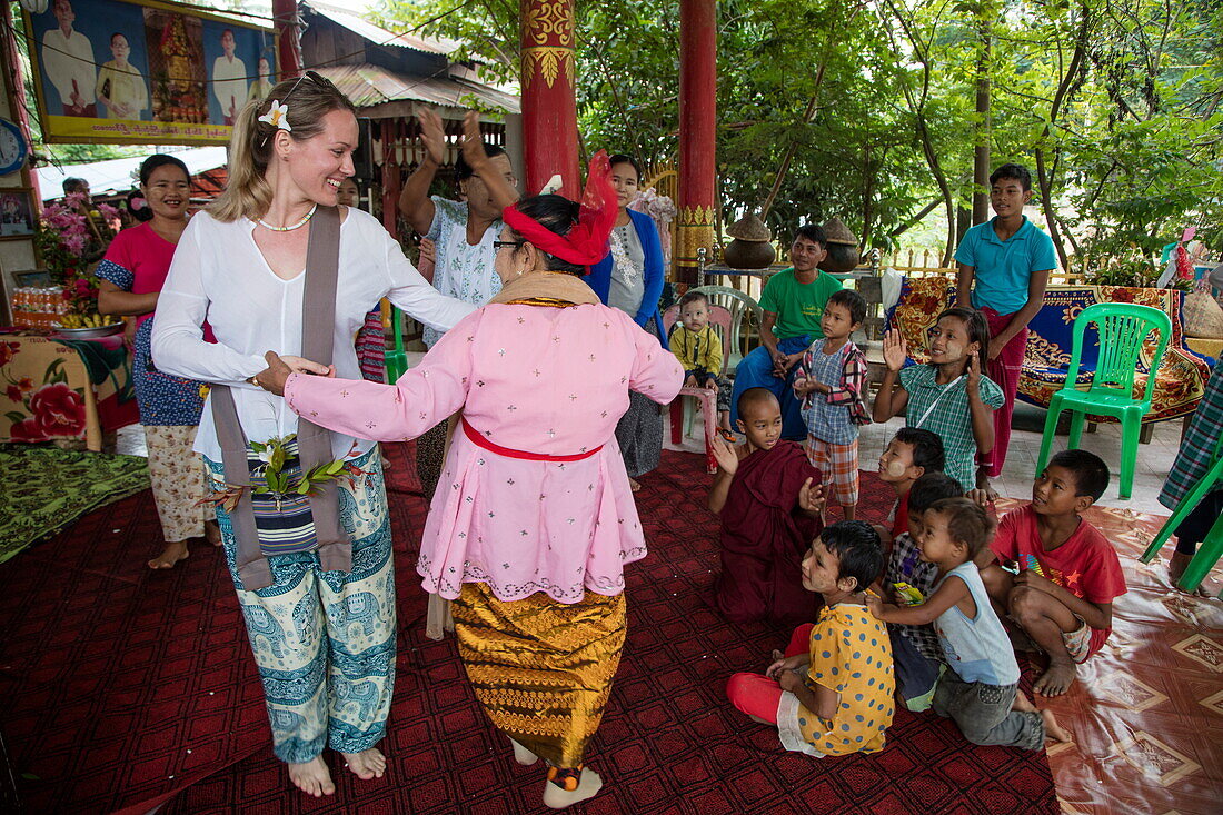 Guest of Ayeyarwady (Irrawaddy) river cruise ship Anawrahta (Heritage Line) dances with locals woman during cultural performance in village, Tagaung, Mandalay, Myanmar