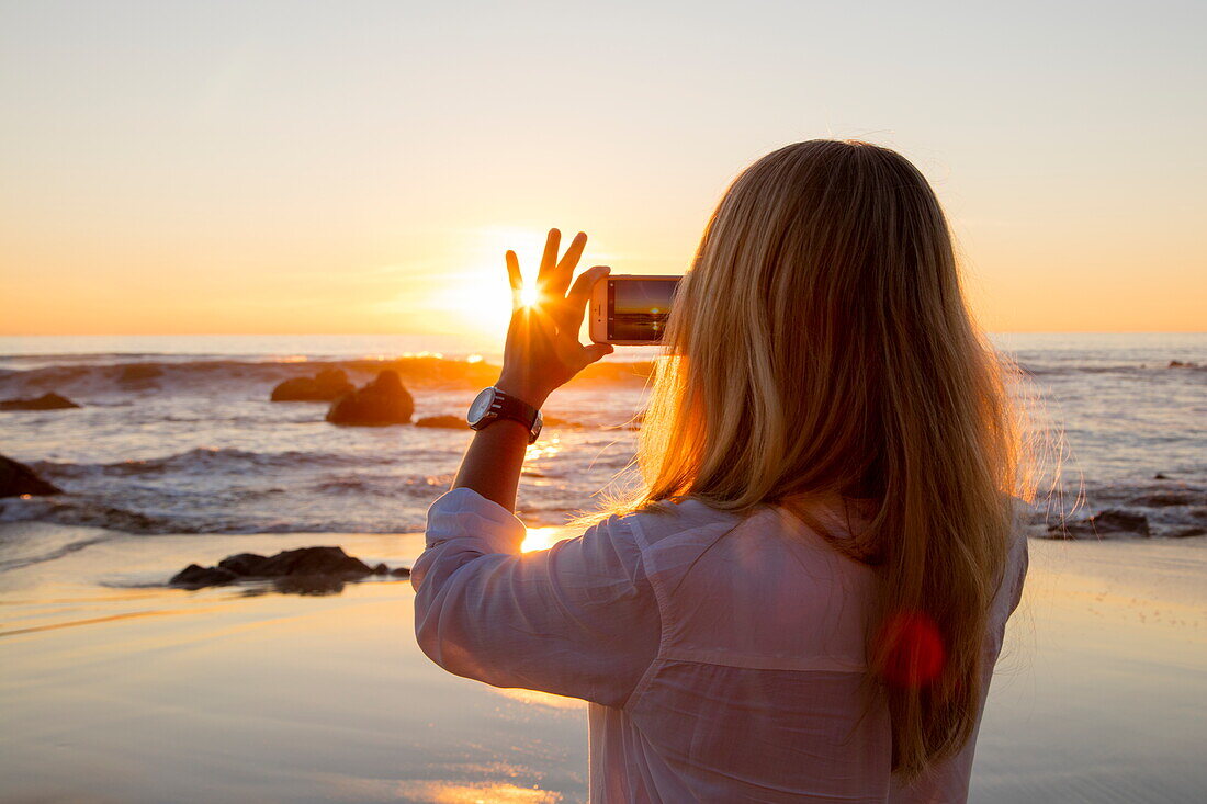 Junge blonde Frau fotografiert Sonnenuntergang am Strand Ngapali Beach mit iPhone, Ngapali, Thandwe, Myanmar