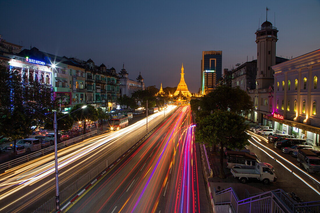 Langzeitbelichtung mit Lichtstreifen von Autos auf der Sule Pagoda Road und die beleuchtete Sule-Pagode in der Abenddämmerung, Yangon, Yangon, Myanmar