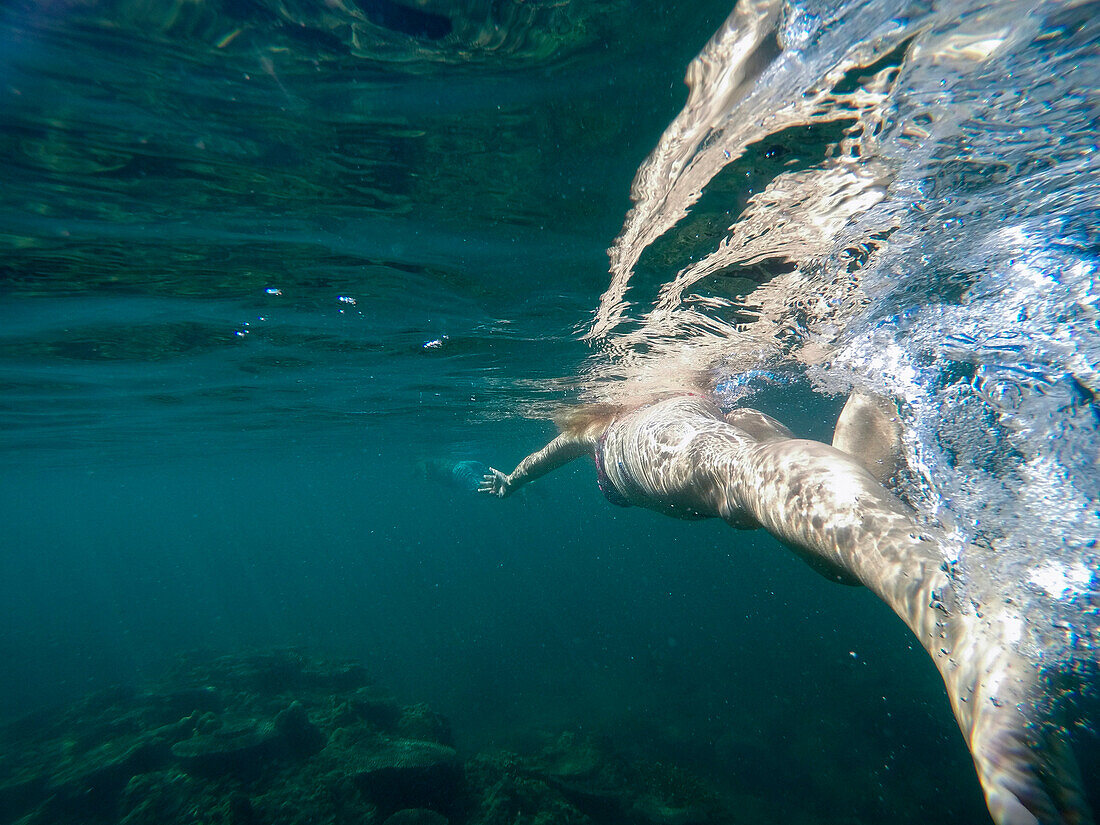 Young woman snorkels in crystal clear water during boat excursion to Maung Shwe Lay village, near Ngapali, Thandwe, Myanmar