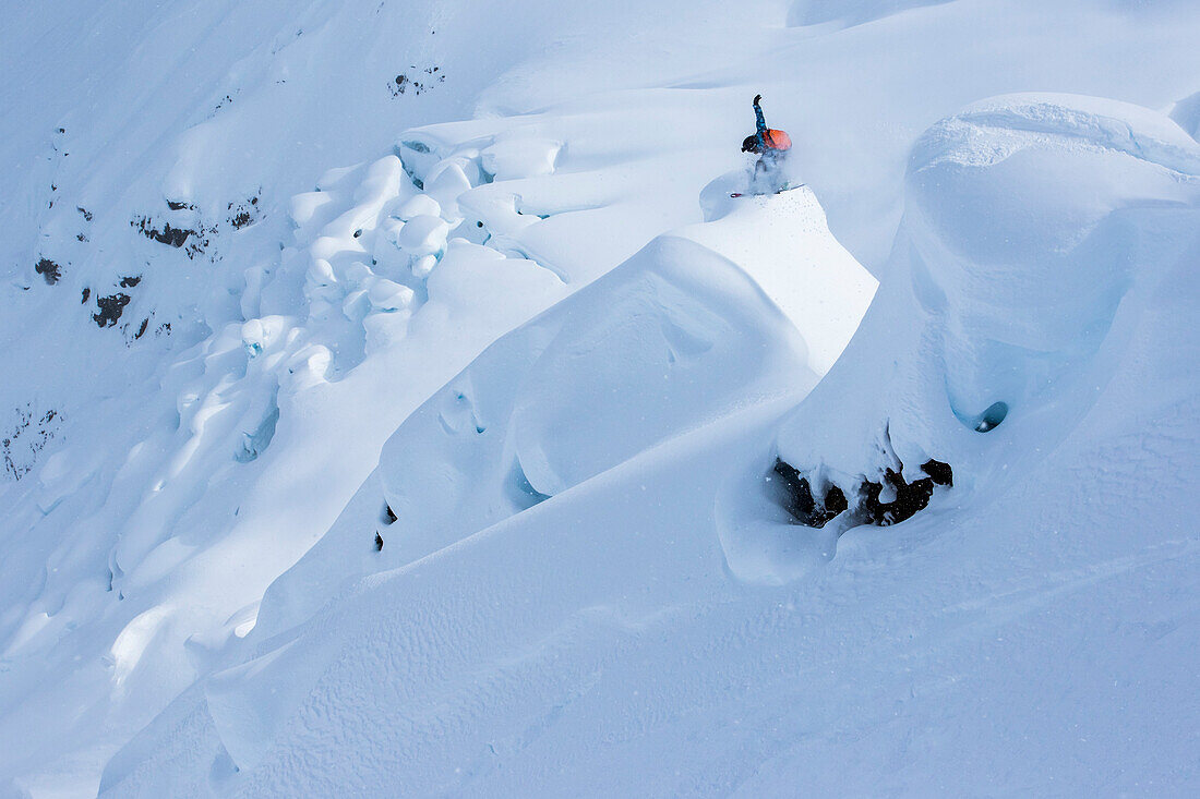 Professional snowboarder Robin Van Gyn catches air and grabs her board on a sunny day while snowboarding in Haines, Alaska.