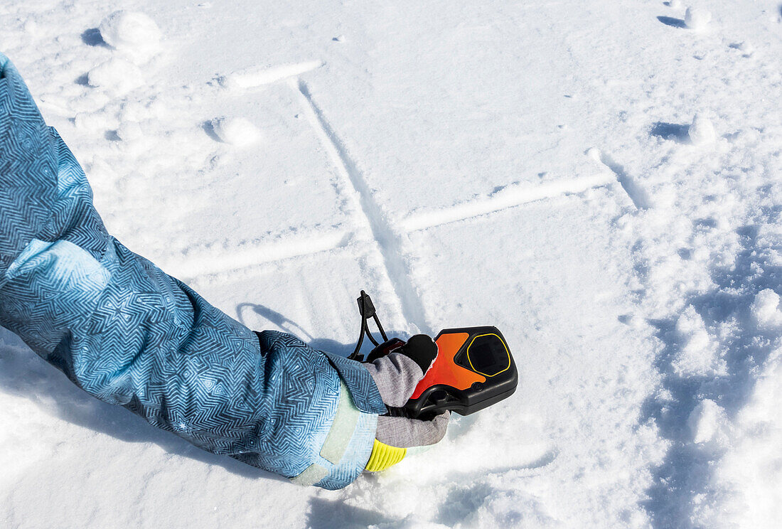 Ein Lawinenbaken und Markierungen im Schnee werden verwendet, um ein Suchmuster zu demonstrieren, das bei der Rastersuche während und bei der Lawinenrettung verwendet wird.