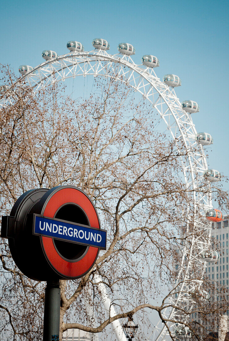 The London Eye Towers over a sign for the London Underground in England