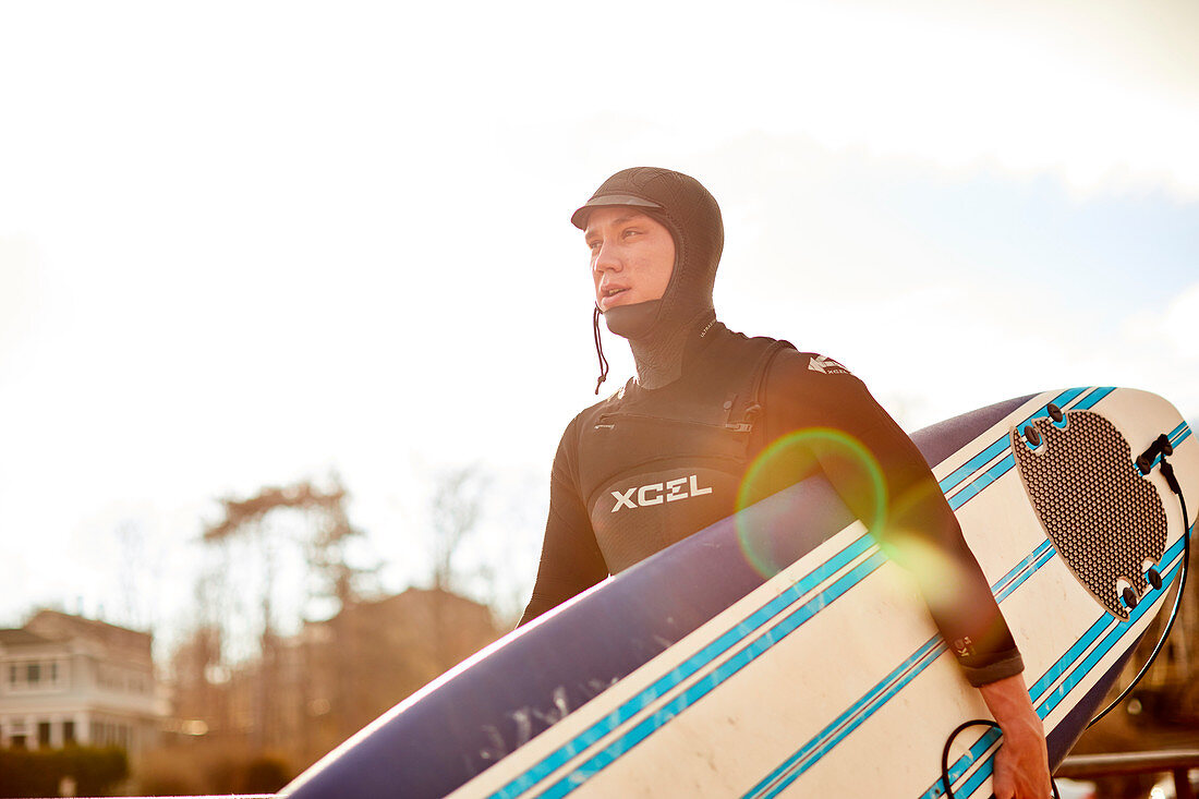 A male surfer carries his surfboard to the beach