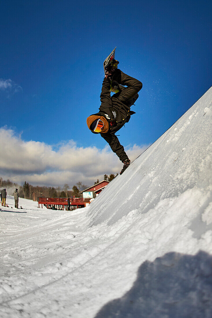 Ein Snowboarder, der ein handplant auf einem Merkmal im Geländepark tut.