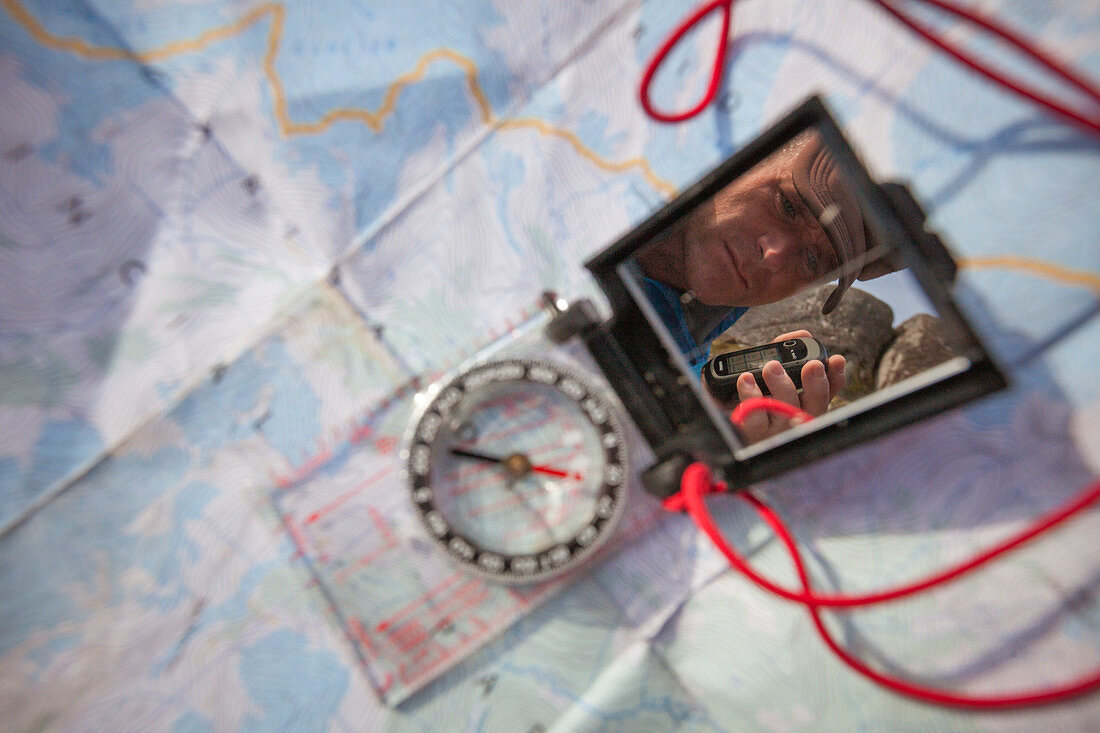 The person holding GPS reflected in the mirror of the navigation compass