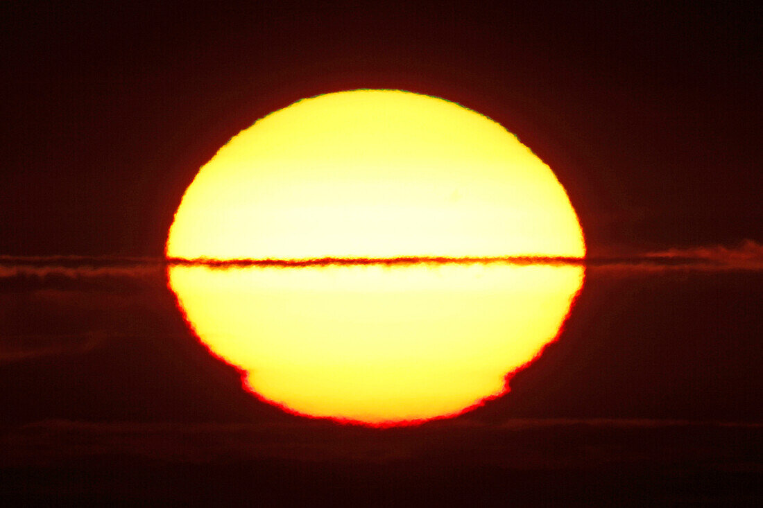 France, Normandy. Closeup of the distorted sun shortly before sunset.