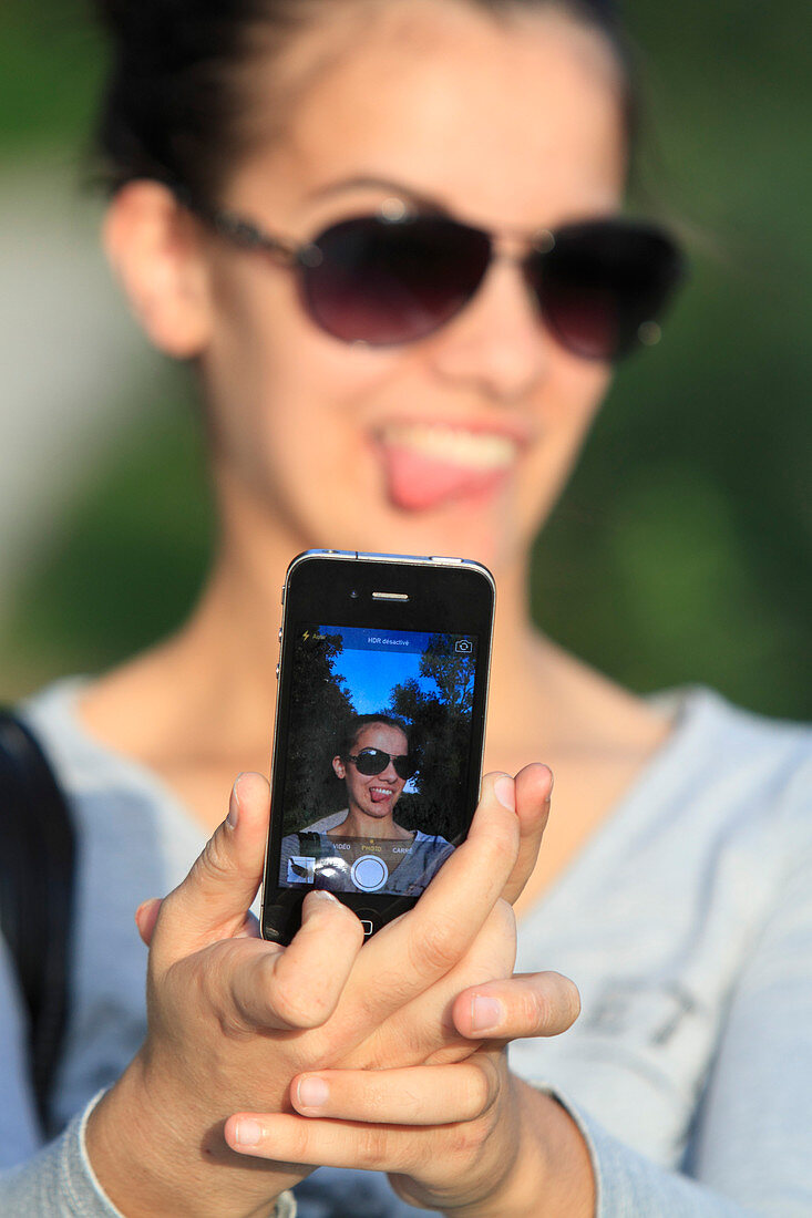 Junge Frau, die ein selfie mit ihrem Smartphone nimmt.