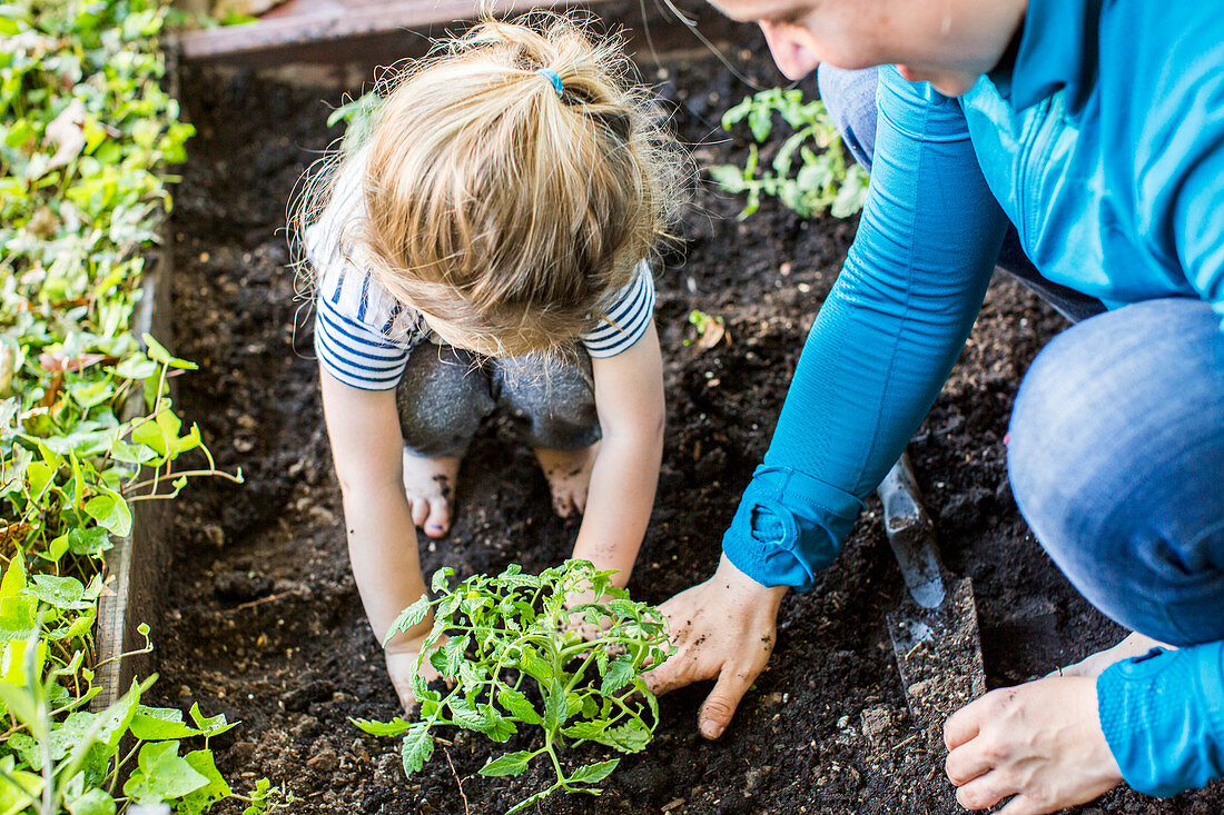 Kaukasische Mutter, die ihrer Tochter Gartenarbeit beibringt