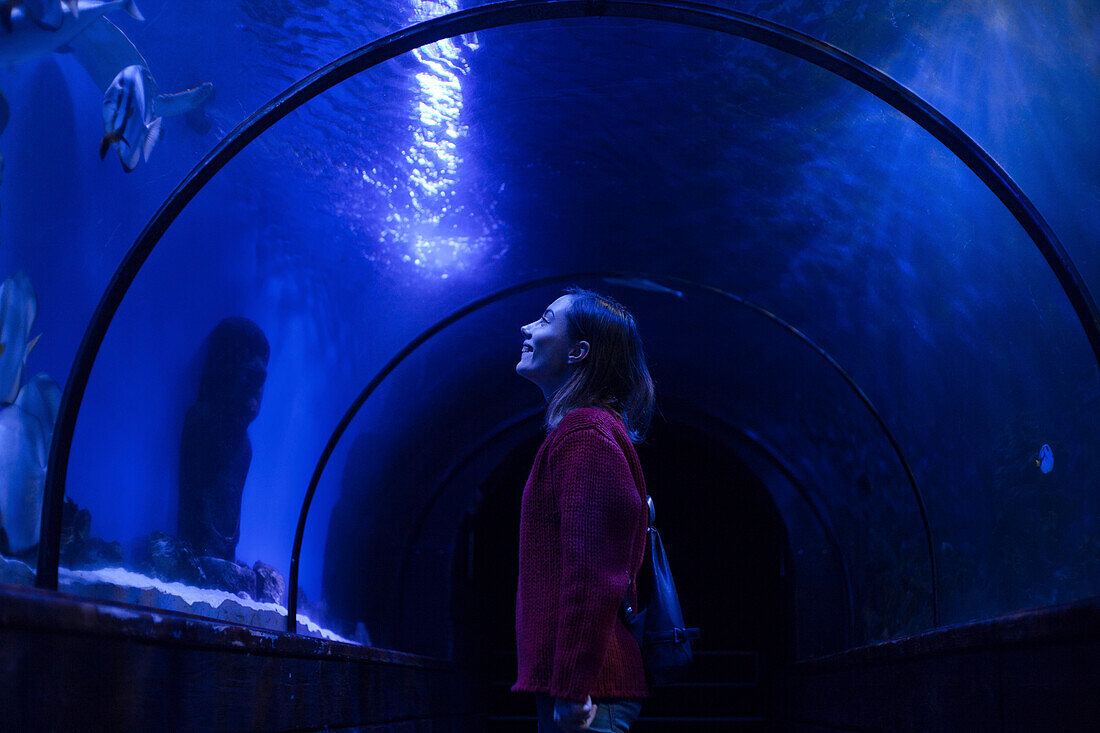 Caucasian woman admiring fish in aquarium