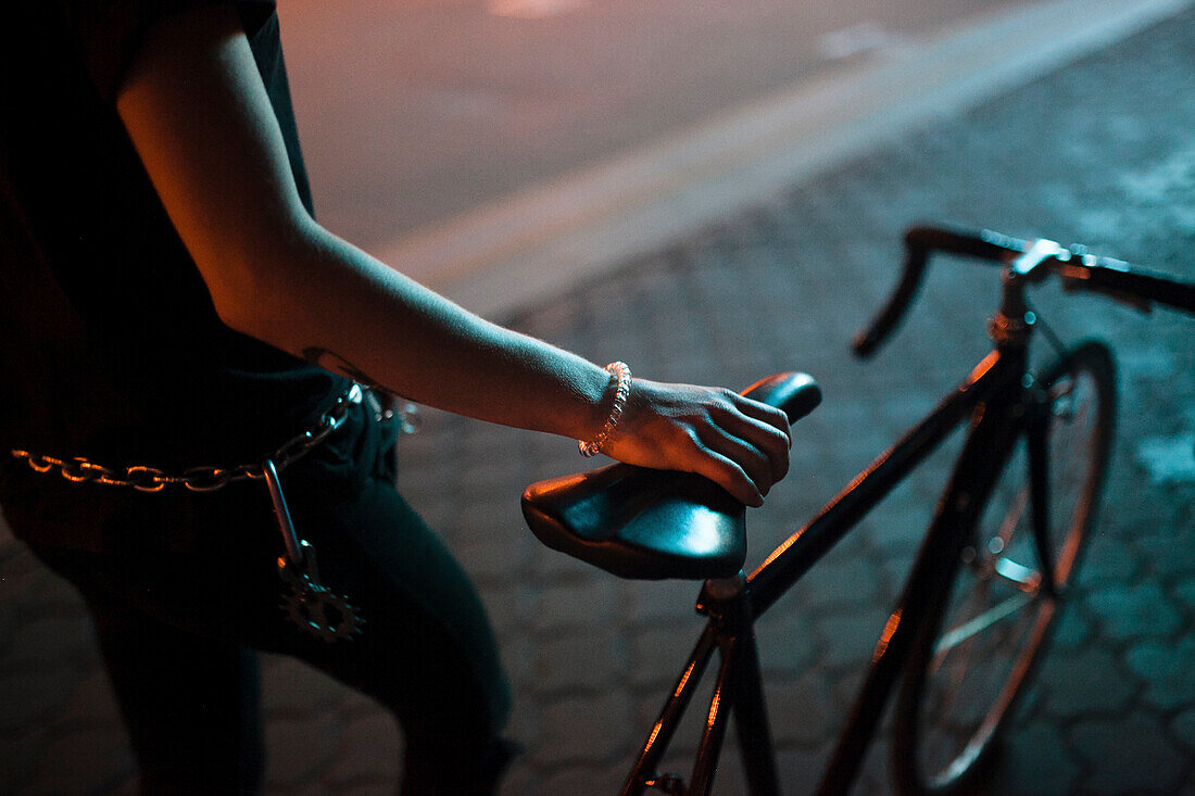 Caucasian man holding a bicycle seat at night