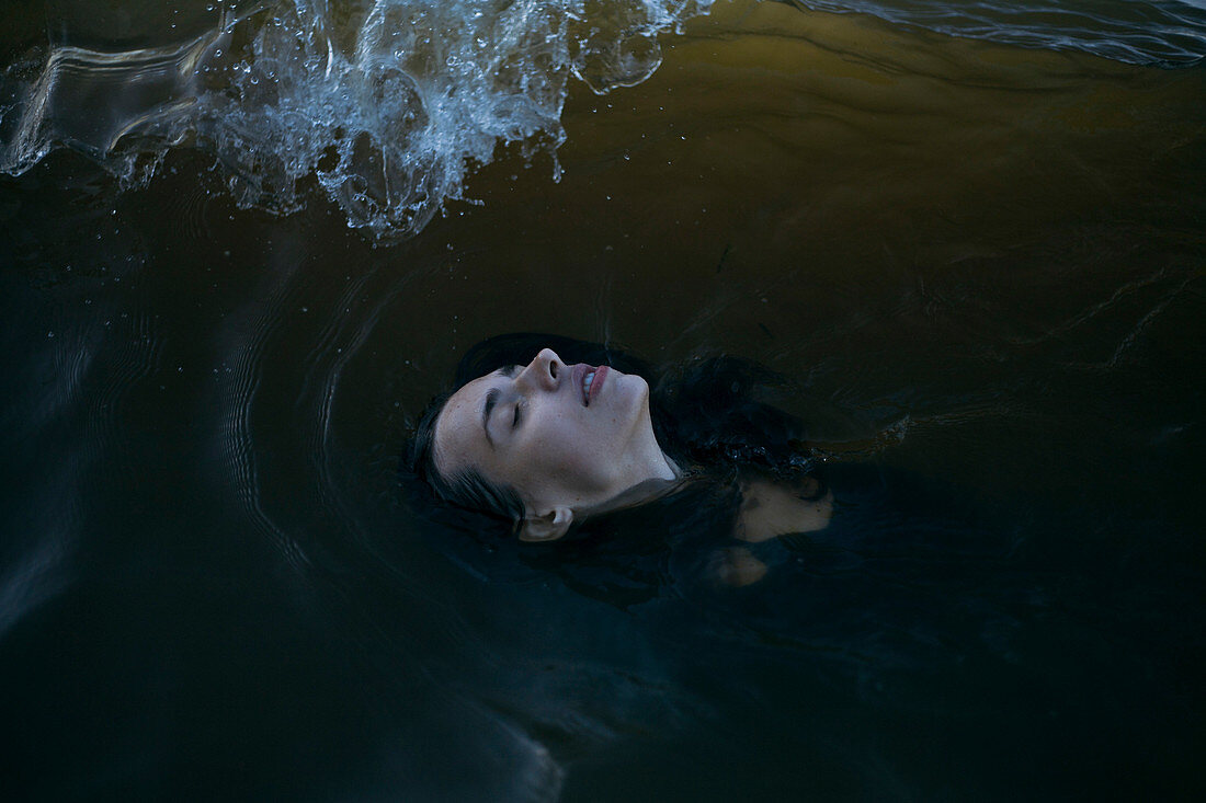 Caucasian woman floating in ocean with eyes closed