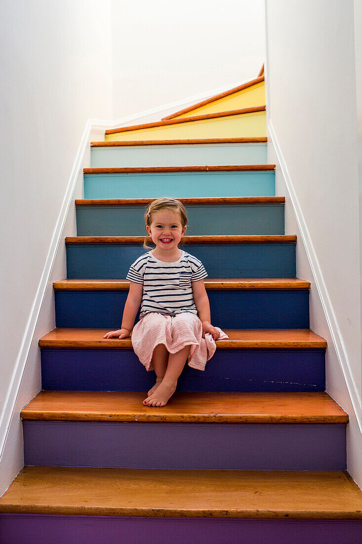 Portrait of smiling Caucasian girl sitting on multicolor staircase