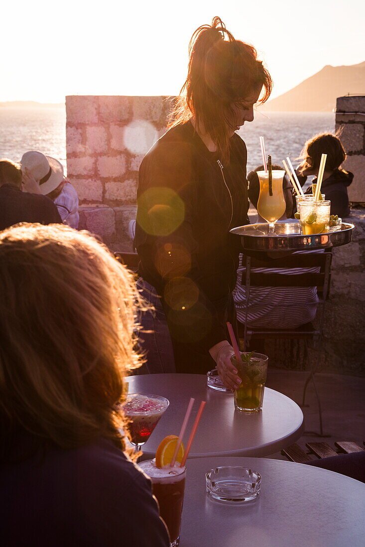Kellnerin serviert Drinks die mit Flaschenzug von der Bar auf das Dach der Massimo Cocktail Bar im alten Festungsturm in der Altstadt gehoben wurden, Korcula, Dubrovnik-Neretva, Kroatien, Europa