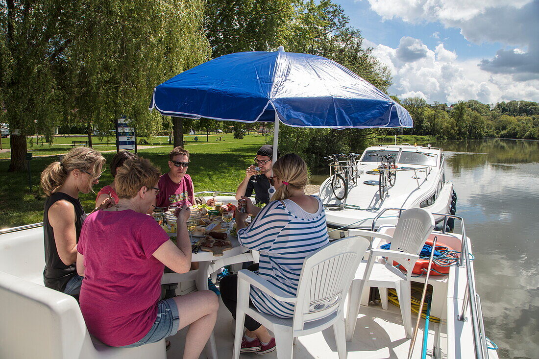 Freunde genießen Mittagessen an Deck von Le Boat Magnifique Hausboot während Bootstörn auf Fluss Petit Saône, Soing, Soing-Cubry-Charentenay, Haute-Saône, Bourgogne Franche-Comté (Burgund), Frankreich, Europa