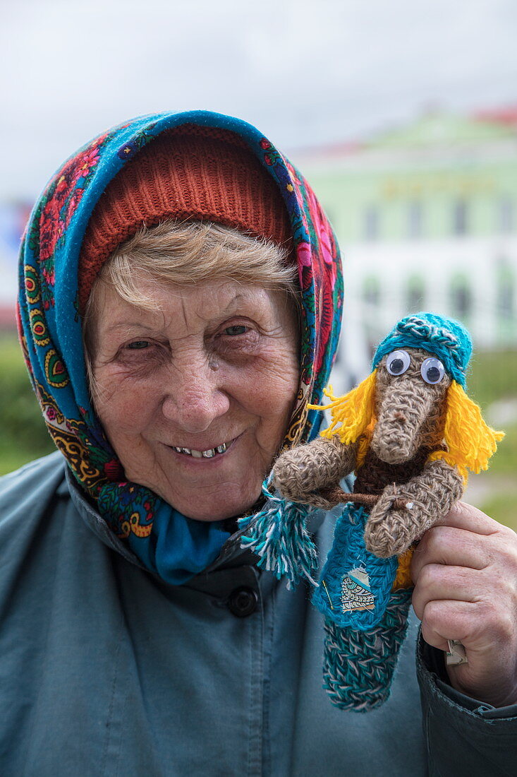 Cheerful elderly woman with self-knit handicraft doll, Uglich, Russia