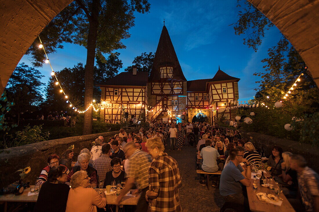 Menschen genießen Frankenwein beim Weinfest am Rödelseer Tor in der Abenddämmerung, Iphofen, Fränkisches Weinland, Franken, Bayern, Deutschland, Europa