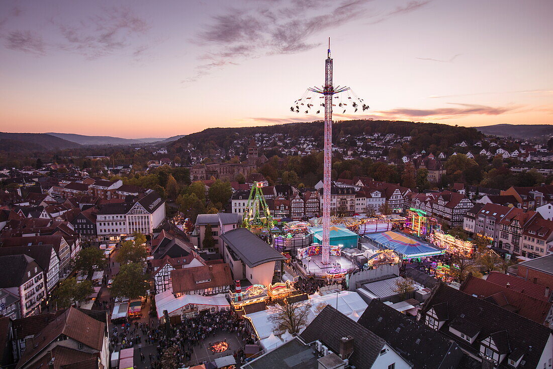 Overhead of Marktplatz market square with amusement rides during Lullusfest carnival celebration at dusk, Bad Hersfeld, Hesse, Germany