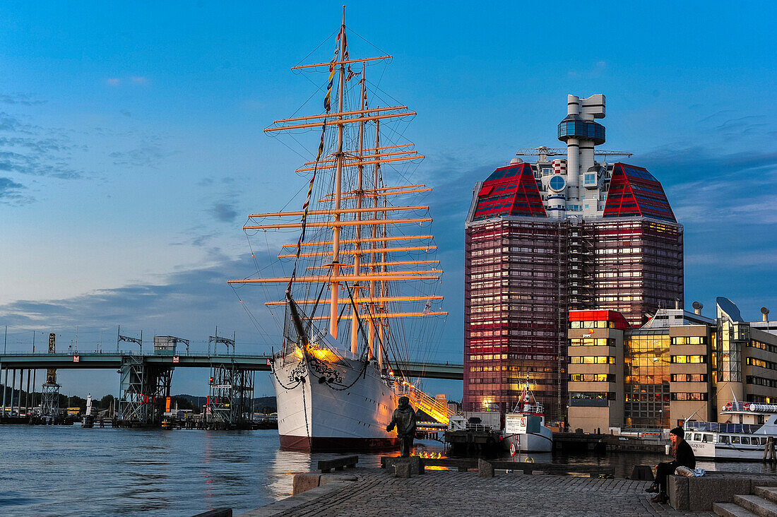 People are sitting in front of Viermastbark Viking and Skanskaskrapan skyscraper in Lilla Bommen harbor, Sweden