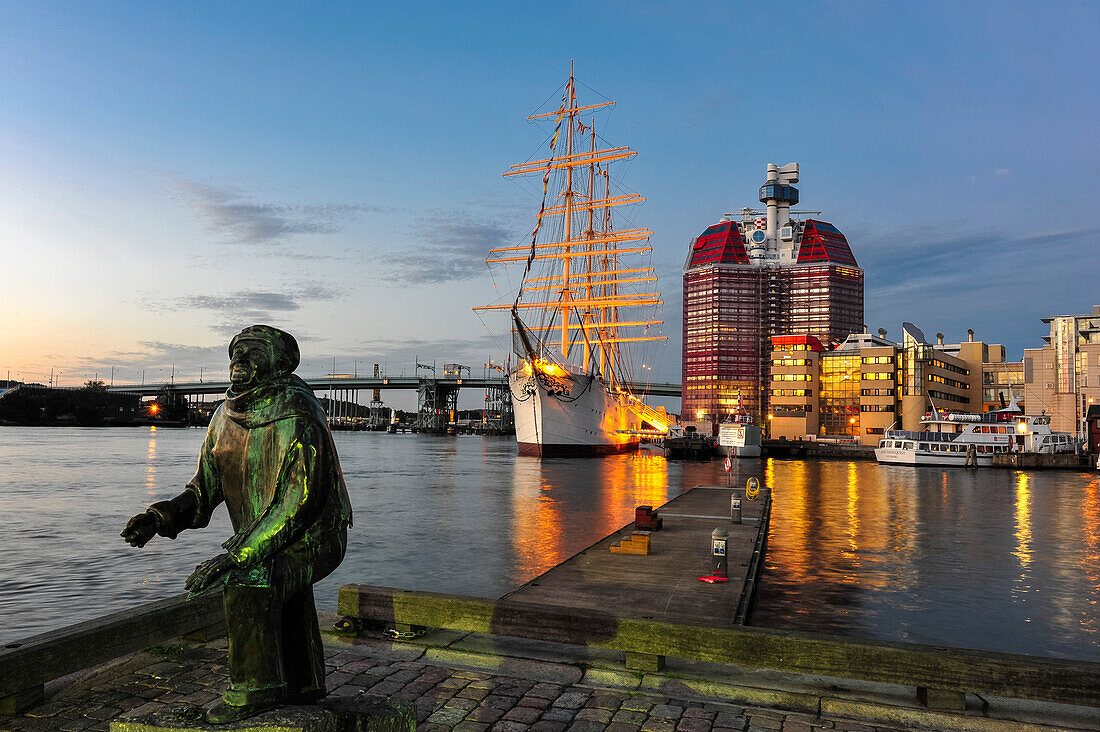 Sculpture of a fisherman in front of four-masted barque Viking and Skanskaskrapan skyscraper in Lilla Bommen harbor, Sweden