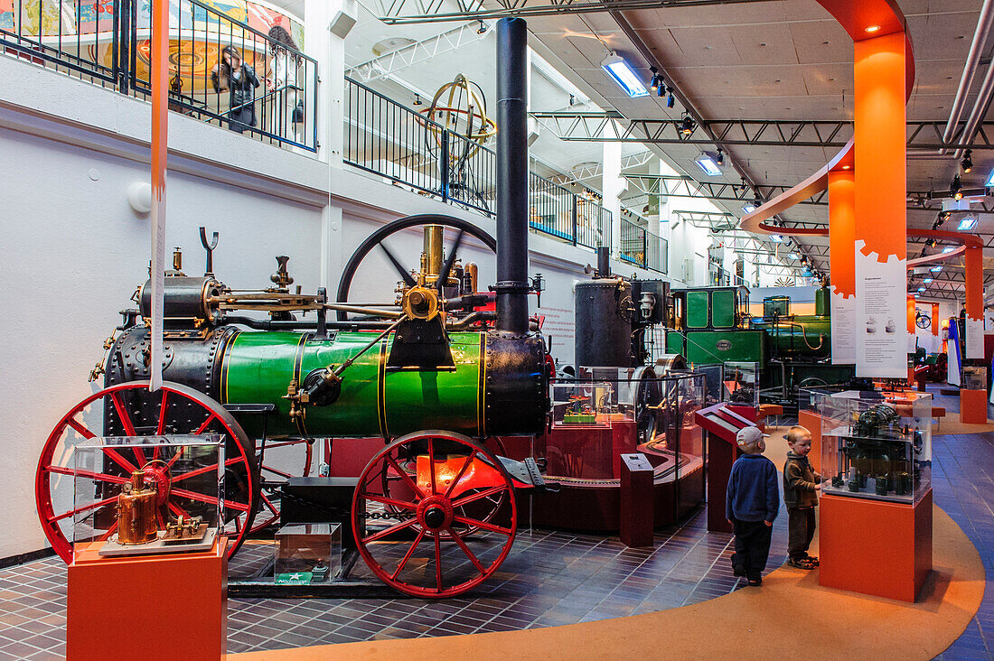 Two boys are standing next to a steam engine in technology and seafaring museum, Malmo, Southern Sweden, Sweden