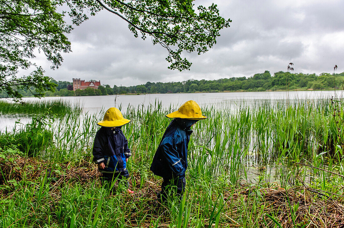 Kinder mit Regensachen vor Schloss Svaneholm am See, Schonen, Südschweden, Schweden