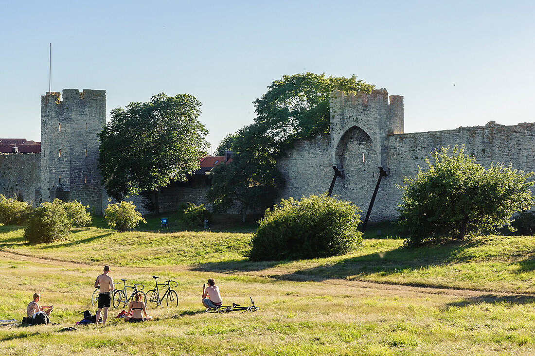 Young people with bicycles at the city wall of the old town of Visby, Schweden