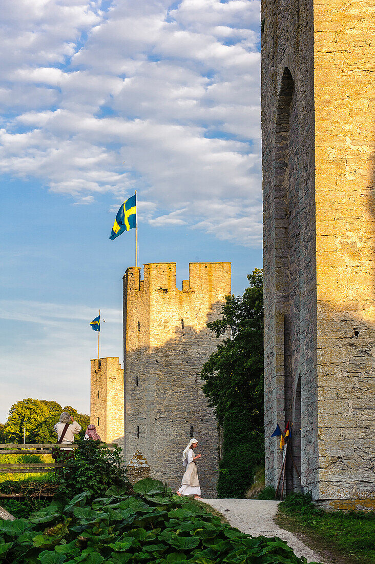Frau mit Kostüm an Stadtmauer mit Turm der Altstadt von Visby , Schweden