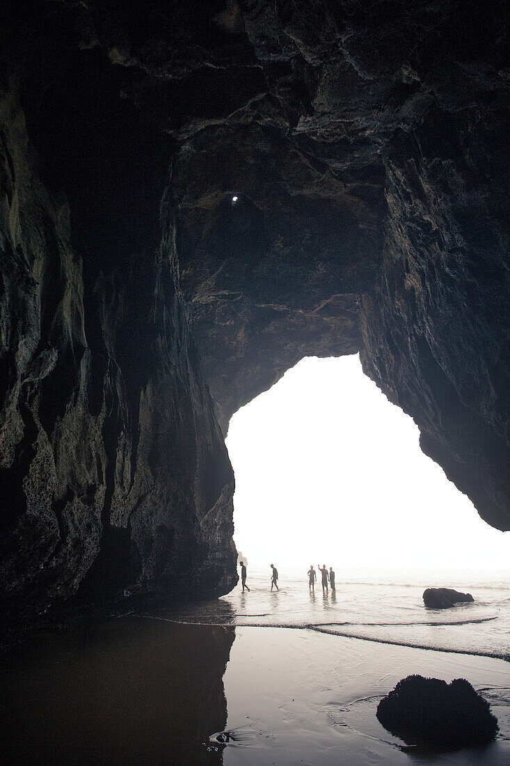 Fünf junge Männer laufen durch eine Höhle am Strand Praia da Amoreira,  Aljezur, Faro, Portugal