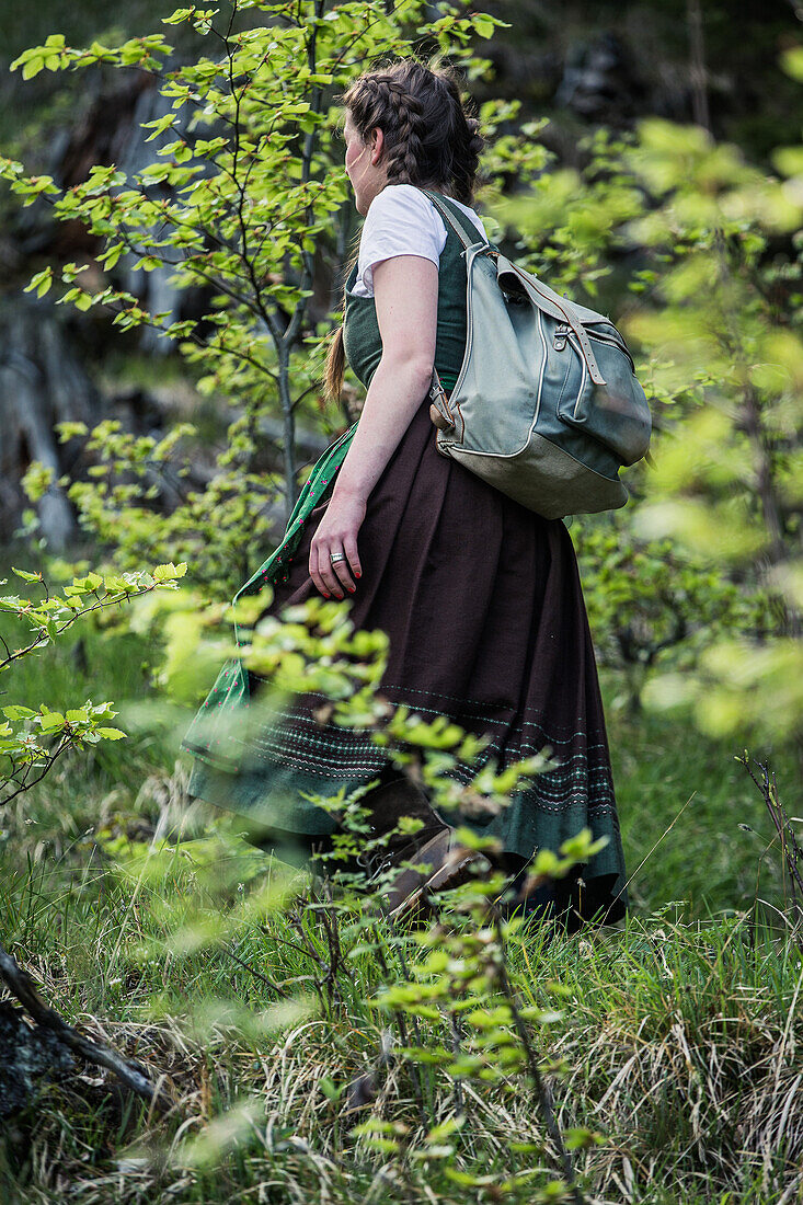 Young woman in traditional costume hiking through the forests on the Falkenstein, Pfronten, Bavaria, Germany