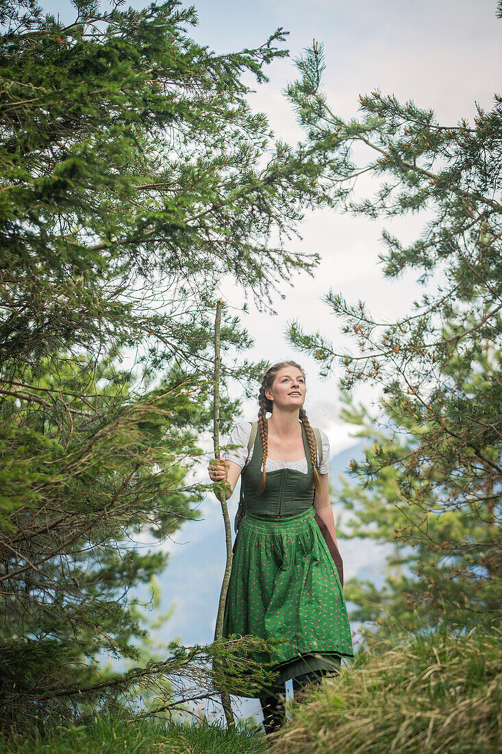 Young woman in traditional costume hiking through the forests on the Falkenstein, Pfronten, Bavaria, Germany