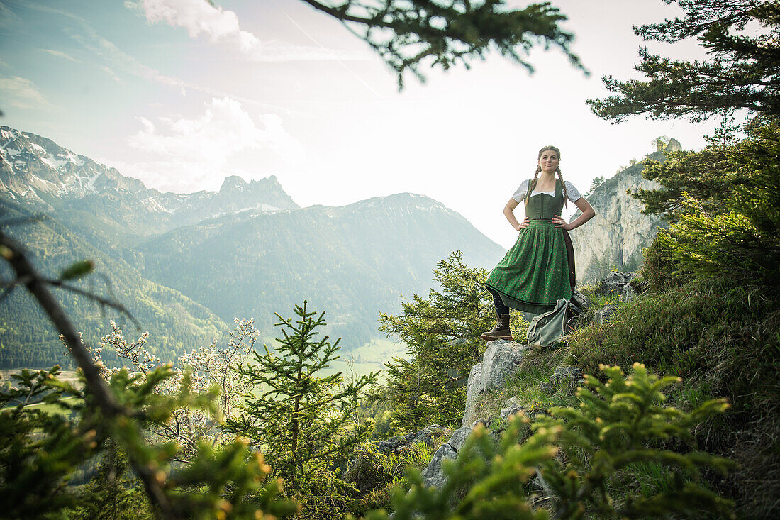 Young woman in traditional costume standing on a rock on the Falkenstein in the Allgaeu, Pfronten, Bavaria, Germany