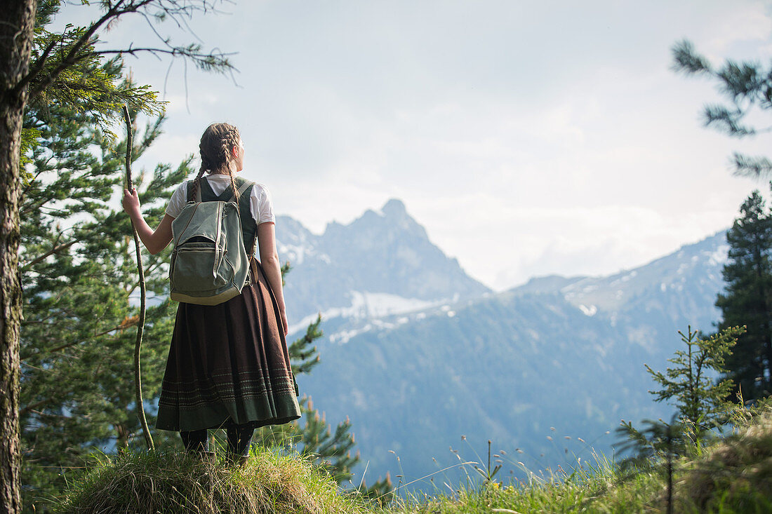 Junge Frau in Tracht genießt den Blick auf den Aggenstein auf dem Falkenstein,  Pfronten, Bayern, Deutschland