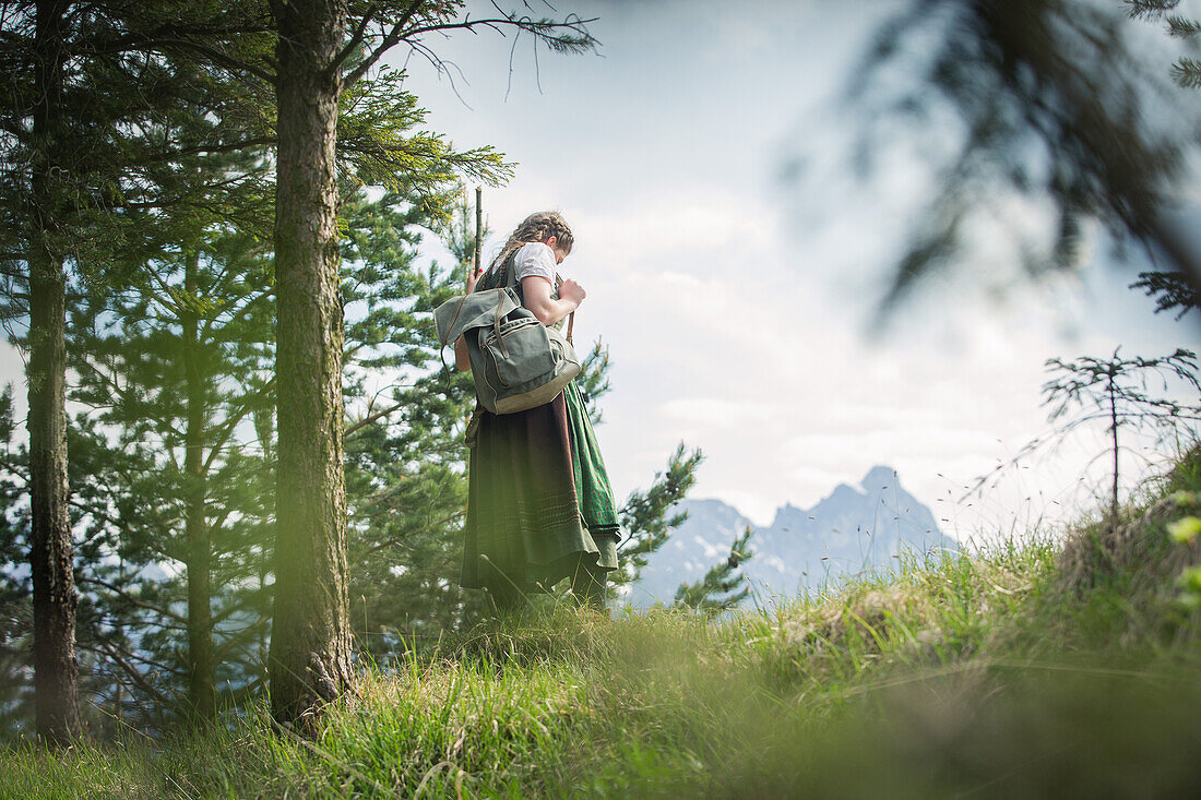 Young woman in traditional costume hiking through the forests on the Falkenstein, Pfronten, Bavaria, Germany