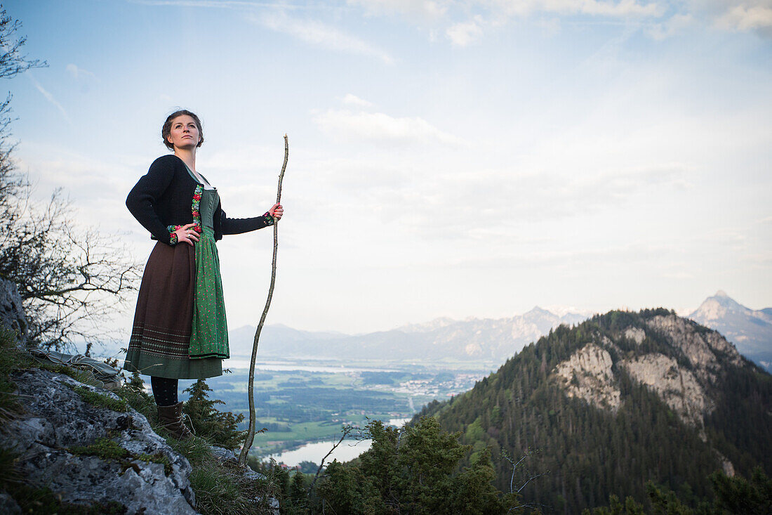 Junge Frau in Tracht steht auf einem Felsen auf dem Falkenstein im Allgäu, Pfronten, Bayern, Deutschland