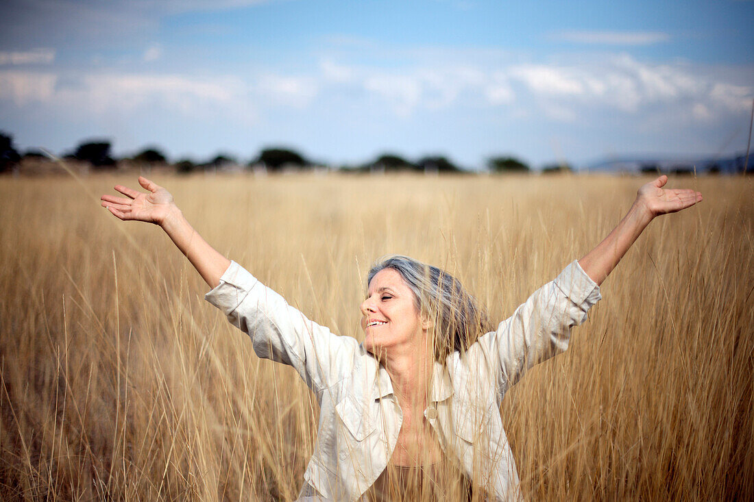 Carefree Caucasian woman standing in field of tall grass