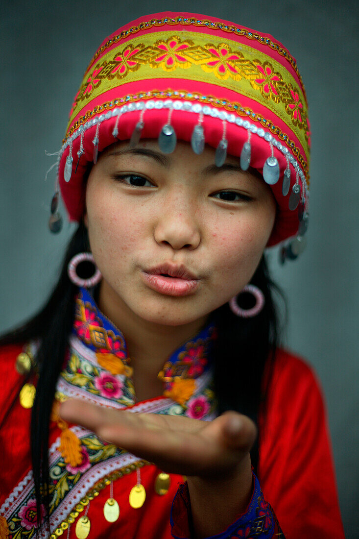 Asian girl wearing traditional hat blowing a kiss