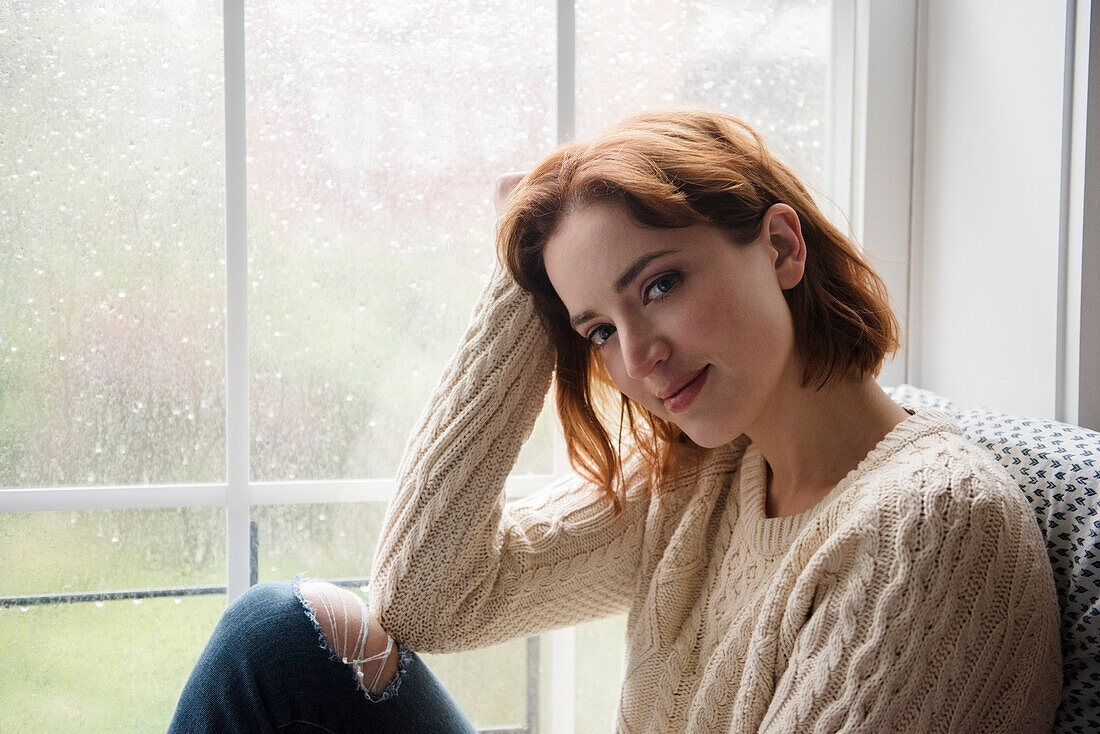 Portrait of smiling Caucasian woman near rainy window