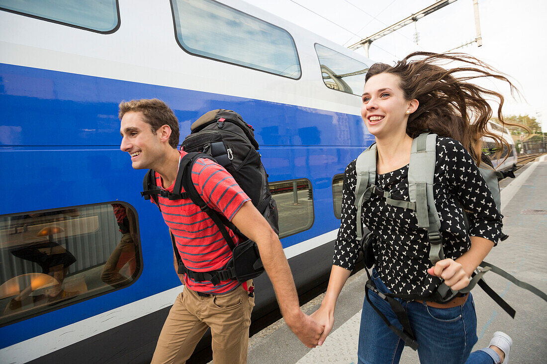 Caucasian couple running near train