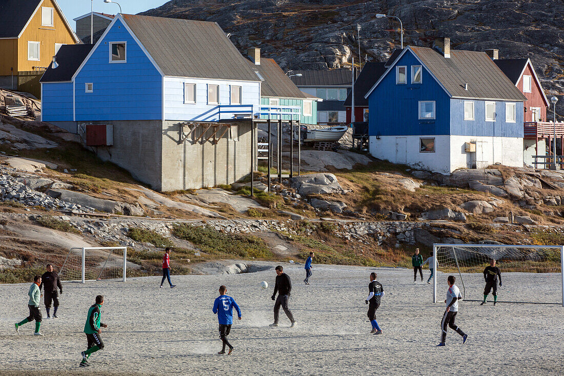 adult men on the soccer field in front of the colorful houses, ilulissat, greenland