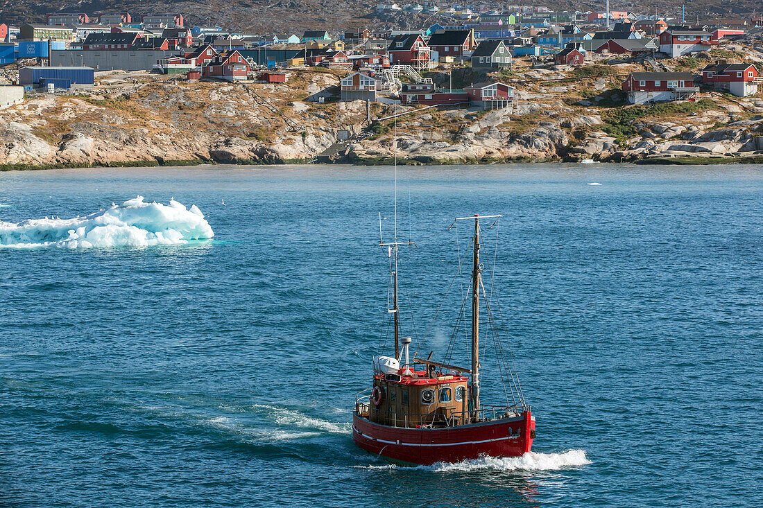 boat in front of the icebergs from the jakobshavn glacier, sermeq kujalleq, and the town of ilulissat, greenland