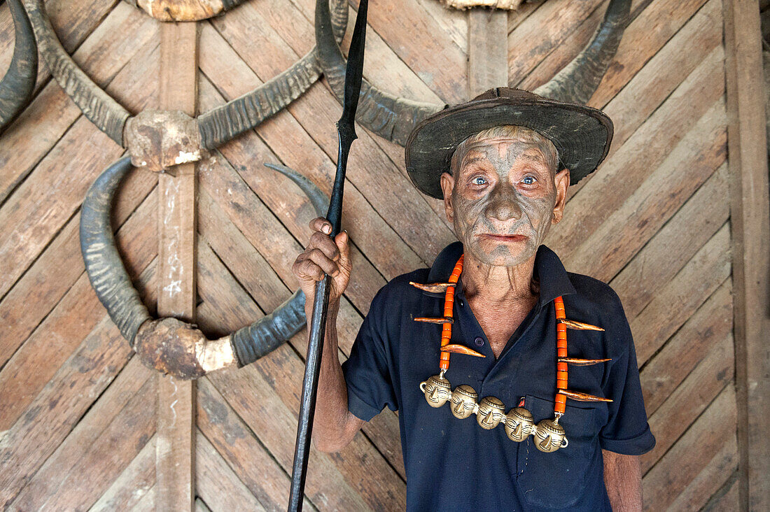 Wangchah Wangsa, Naga headhunter, with tattooed face and Naga tribal necklace, holding hunting spear, Longwa village, Nagaland, India, Asia