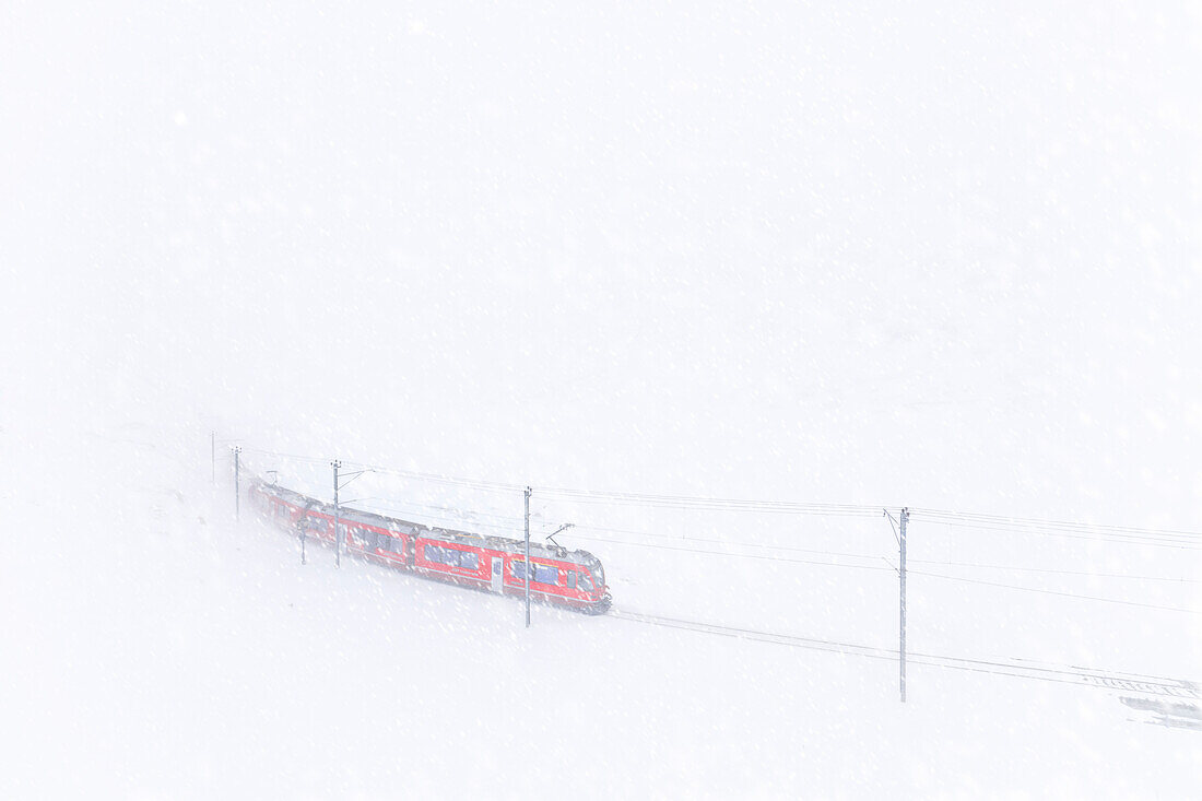 Bernina Express train at Bernina Pass during a snowstorm, Engadine, Canton of Graubunden, Switzerland, Europe