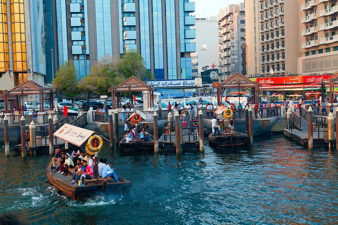 A water taxi carrying passengers arrives at a busy dock, Dubai Creek, Dubai, United Arab Emirates, Middle East